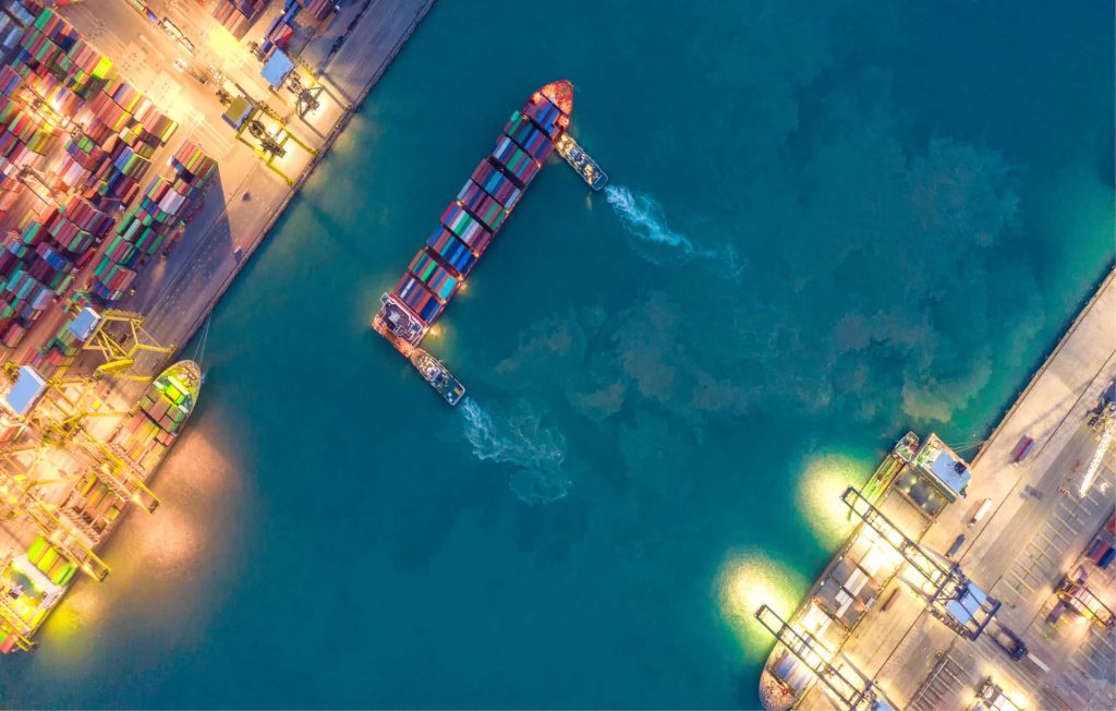 Top view of a container ship at a lit-up port.